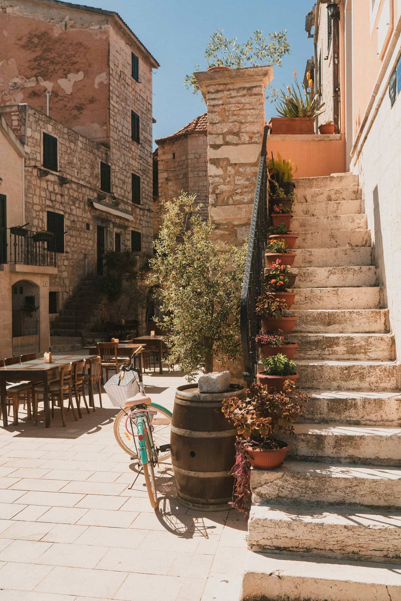 Stone steps and stone houses on a lane. Tables are set out along the lane.